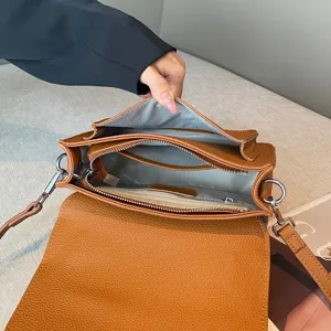Brown genuine leather messenger bag detail showing multi-compartment interior and durable zippers.