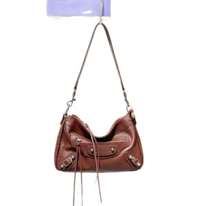 Sac bandouliere en cuir marron style moto avec rivets metalliques et franges pour femmes.