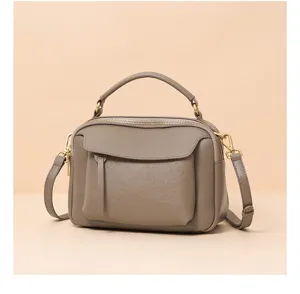 Detail view of the elegant grey leather handbag featuring a top handle and shoulder strap.