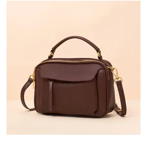 Detailed view of the elegant dark brown leather handbag featuring golden hardware and top handle.
