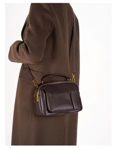 Dark brown leather Boston handbag detail shot, vintage crossbody bag with metal hardware.