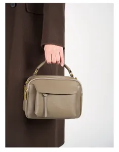 Detail view of genuine leather retro handbag with top handle and front pocket design.