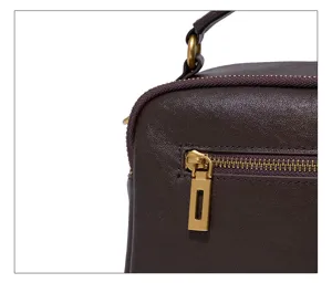 Close-up detail shot of the brown leather handbag zipper and metallic hardware craftsmanship.