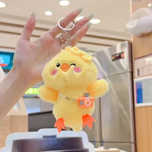 Cute fluffy yellow duck plush keychain close-up, soft chick toy bag charm with mini camera.