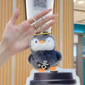 Plush penguin keychain detail, cute fluffy stuffed animal toy with mini camera and sunglasses.