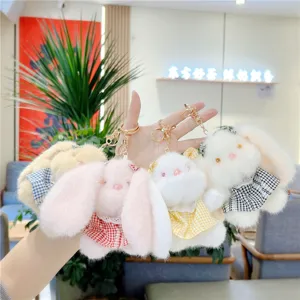 Detail view of fluffy plush bunny keychains with cute plaid dresses and gold clasps.