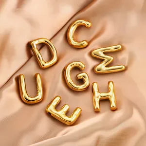 Close-up of shiny gold puffy letter charms, smooth satin background for jewelry DIY.