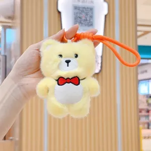 Detail view of a cute yellow plush bear keychain pendant with a red bow tie for keys.