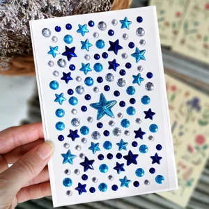 Detailopname van een vel met blauwe en heldere stervormige acryl edelsteenstickers
