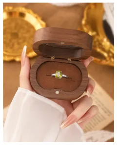 Detail view of elegant peridot gemstone ring in a wooden gift box held by hand.