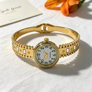 Detailansicht einer goldfarbenen Damen-Armbanduhr mit floralem Ausschnitt und Kristallen