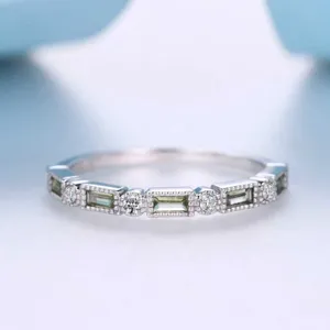 Detailopname van vintage milgrain ring met olijfgroene baguette- en ronde edelstenen.