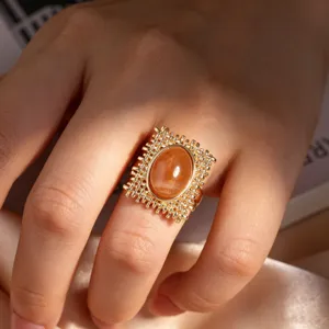 Nahaufnahme eines vintage goldfarbenen offenen Rings mit einem bernsteinfarbenen Ovalstein.