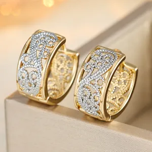 Close-up detail of vintage two-tone gold and silver filigree hoop earrings with cut-out design.