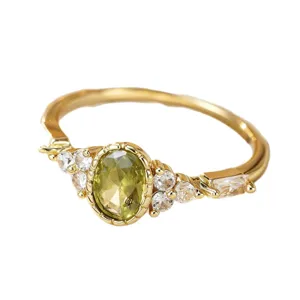 Elegant gold-plated ring featuring an oval olive-green zirconia and sparkling side stones.