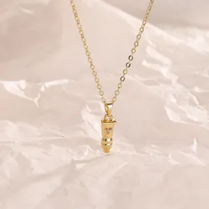 Close-up of gold 3d bullet pendant necklace with heart detail, trendy niche clavicle chain jewelry.