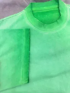 Green distressed heavy cotton t-shirt detail showing raw edge collar and short sleeves.