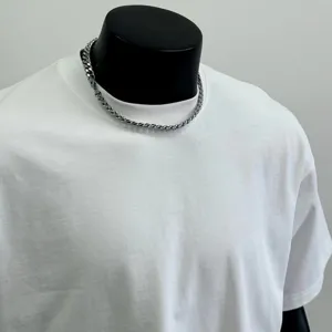 Detailed close-up view of a stylish silver chain necklace displayed on a sleek black mannequin.