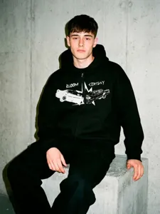 Vue détaillée du sweat à capuche noir avec imprimé graphique de voiture et style streetwear.