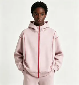 Detailed view of the oversized pink zip-up hoodie featuring contrast red stitching and dual zippers.