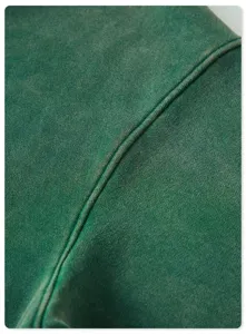 Dark green vintage washed hoodie fabric detail showing heavyweight texture and seams.