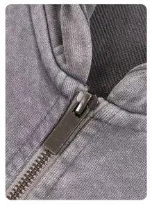 Close-up detail of grey washed fleece zip hoodie, showing zipper and fabric texture.