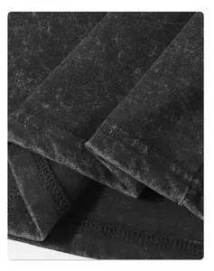 Detail view of distressed washed black cotton t-shirt fabric, showing fine double-needle stitching and vintage texture.