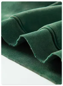 Detailed shot of dark green heavyweight washed hoodie ribbed cuff, retro style fabric texture.
