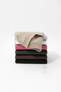 Detail view of a stacked collection of solid color crew neck short sleeve t-shirts for men.