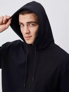 Detail view of a men's heavy black hoodie sweatshirt, showing the comfortable hood and fabric.