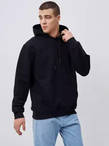 Detail shot of a heavy solid black hooded sweatshirt featuring a cozy pocket and adjustable drawstring.