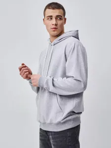 Detailed view of grey hooded sweatshirt worn by model, showing drawstring and pocket style.