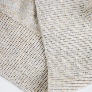 Nahaufnahme des grob gerippten Strickpullover-Stoffes für Herren in meliertem Beige.