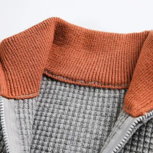 Gros-plan sur le col de pull en tricot gaufré pour homme et les détails de tissu gris.