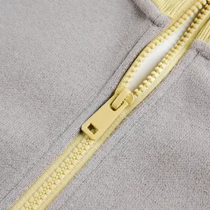 Close-up detail of color-blocked zipper and textured fabric for autumn winter hoodies.