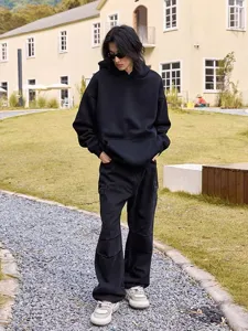 Outdoor street style scene showcasing a loose black hoodie outfit with cargo pants.