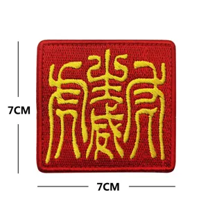 Detalle del parche bordado rojo cuadrado con un diseño amarillo artístico de 7x7 cm.