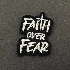 Embroidered patch detail featuring faith over fear text lettering, dark aesthetic backdrop.