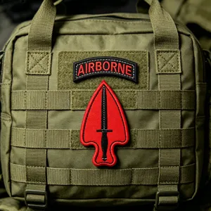 Detailed view of green tactical pouch featuring embroidered Airborne dagger morale patch and MOLLE web.