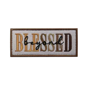 Primer plano detallado del parche moral táctico bordado con diseño de tipografía BLESSED.