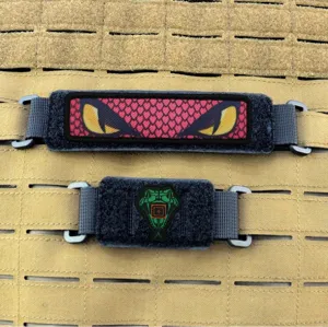 Vista detallada del conector de cinta MOLLE táctico con base de velcro y clips metálicos.