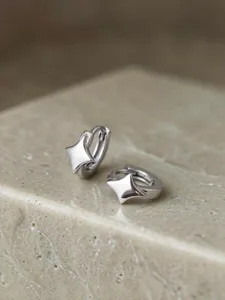 Nahaufnahme von Sterling Silber vierzackigen Stern Creolen auf einer Steinoberfläche.