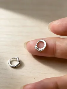 Nahaufnahme Detail der kleinen Silbercreolen mit vierzackigem Sternanhang für den Alltag.