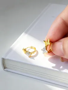 Nahaufnahme der goldenen Schmetterling Huggie Creolen mit funkelnden Zirkonia Steinen.