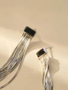 Exquisite Detailansicht langer Sterling Silber Fransen Ohrringe mit eleganten schwarzen Steinen.