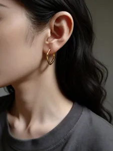 Detailaufnahme getragener minimalistischer goldener geometrischer Creolen, elegant.