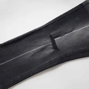 Dettaglio ravvicinato del ginocchio strappato su jeans flare neri vintage da donna