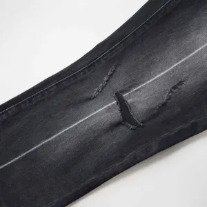 Vista macro del denim nero invecchiato con strappi e dettagli di texture sbiaditi