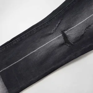 Dettaglio del ginocchio strappato e del lavaggio sbiadito sui jeans a zampa neri vintage