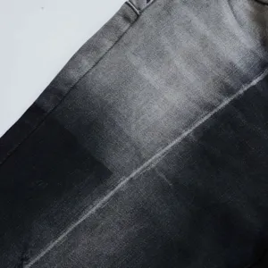 Primo piano della trama del denim lavato sfumato nero-grigio vintage su jeans a zampa